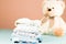 Newborn baby clothes laundry washed, ironed and stacked on pink background with a teddy bear