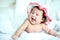 Newborn Baby with Colorful Floppy Hat Lying Down on a White Blanket