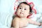 Newborn Baby with Colorful Floppy Hat Lying Down on a White Blanket