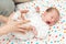 Newborn baby dressed in white laying on her back