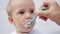 Newborn baby eats from a spoon, close-up portrait grimy face. Newborn baby at home kid dream concept. Newborn baby son