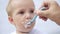 newborn baby eats from a spoon, close-up portrait grimy face. newborn baby at home kid dream concept. Newborn baby son