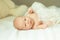 Newborn baby girl in a beautiful bonnet lying on a blanket.