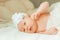 Newborn baby girl in a beautiful bonnet lying on a blanket.
