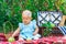 Newborn baby girl in a blue dress on a picnic. A toddler 9-12 months old grabs a green apple lying on a blanket