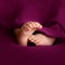 Newborn baby girl feet on raspberry background in square compositon