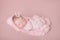 Newborn baby girl in a pink cocoon on a pink background, sleeping princess with a crown