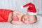 Newborn baby girl in red santa hat sleeping with a gift in hands