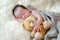 Newborn baby girl sleeps with a toy teddy bear