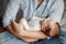 Newborn baby holding father parent finger while sleeping. Parent holding rocking child daughter son in hands. Authentic lifestyle