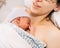 Newborn baby in hospital after just being born, mother holding him and breastfeeding in hospital bed