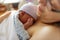 Newborn baby in hospital after just being born, mother holding him and breastfeeding in hospital bed