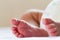 Newborn baby infant feet on white bed