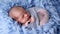 Newborn baby lying in blue fur wrapped in diaper