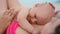 Newborn baby lying on mother breast at beach. Mom enjoying vacation with baby