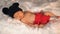 Newborn baby in mouse costume sleeping on fur bed