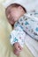 Newborn baby sleeping in bed, focus on hands with small fingers, blurred head and face