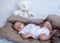 Newborn baby sleeping full length with white teddy bear in background