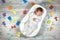 Newborn baby sleeps in a special orthopedic mattress Baby cocoon, on a wooden floor multicolored letters around. Calm