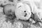 Newborn baby sleeps with a teddy bear black and white
