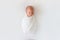 Newborn baby sleeps in white winding on a white background