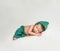 Newborn boy in green suit sleeping on blanket