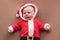 Newborn girl dressed in santa claus costume looking at camera with confused face.