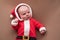Newborn girl dressed in santa claus costume looking at camera with confused face.