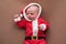 Newborn girl dressed in santa claus costume looking at camera with confused face.