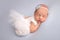 Newborn girl in the first days of life in a white ballet dress white bandage