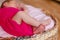 Newborn girl in pink bodysuit barefoot lies in round crib and sleeps