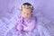 A newborn girl sweetly sleeping in a cocoon on a lilac background fur in a beautiful cap, art photo of a newborn baby