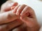 Newborn holds mum s finger, close-up