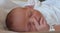 Newborn identified with a name tape is touching his nose