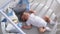 Newborn lies in the round white bed with mobile