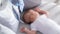 Newborn lies in the round white bed with mobile