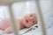 The newborn is lying in a crib with white rods. The child looks through the bars of the white bed. Meaningful look of a newborn. A