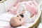 Newborn pink cradle hold black pacifier hand