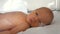 A newborn preterm baby in a plastic crib lies close up