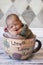 Newborn sleeping in giant coffee cup