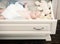 Newborn toddler with blue eyes and curious face. Baby lying in white wooden chest drawer