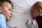 Newborn and toddler laying on the white bed with dummy