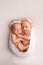 A newborn twin sleeps next to his sister Newborn twin girls on the background of a white blanket with pink bandages.