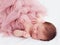 Newborn, two weeks old baby girl in ruffle dress and with finger ring is sleeping peacefully