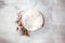 Newborn winter background - round cream bowl with CHristmas red berries and snow covered branches  garland on white backdrop