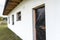 A newly applied layer of white silicone plaster on the wall of the house, the window and door are secured with black foil.