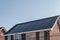 Newly build houses with solar panels attached on the roof against a sunny sky Close up of new building with black solar