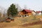 Newly built modern wooden log house with big open porch in front on side of small hill above small wooden storage shed