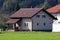 Newly built small suburban family house with front porch and new roof tiles surrounded with old houses and dense forest