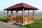 Newly built wooden gazebo structure with new roof mounted on concrete foundation with wooden table and chairs overlooking houses